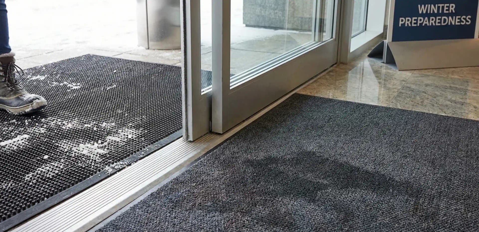 Professional commercial floor mat system at office entrance capturing winter salt and snow
